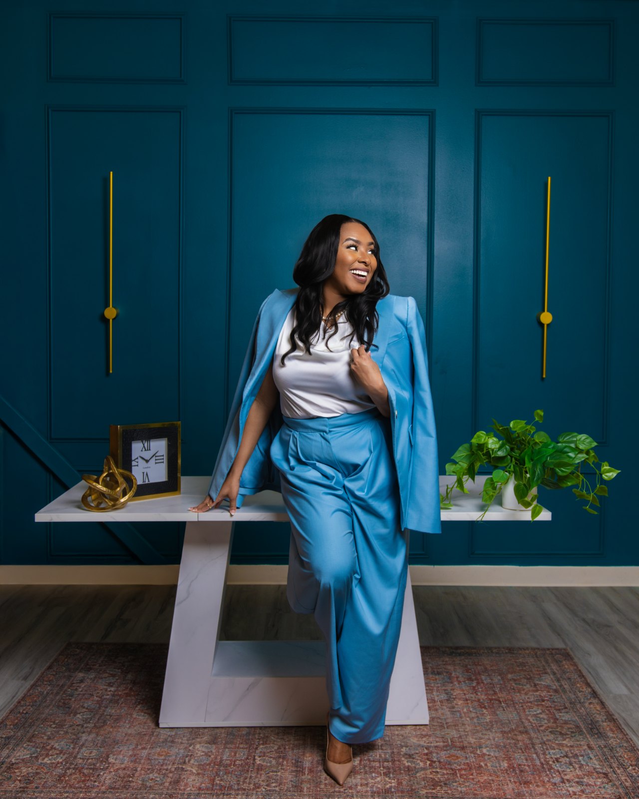 Dr. Desiree Strickland leaning against a marble console, blue suit.